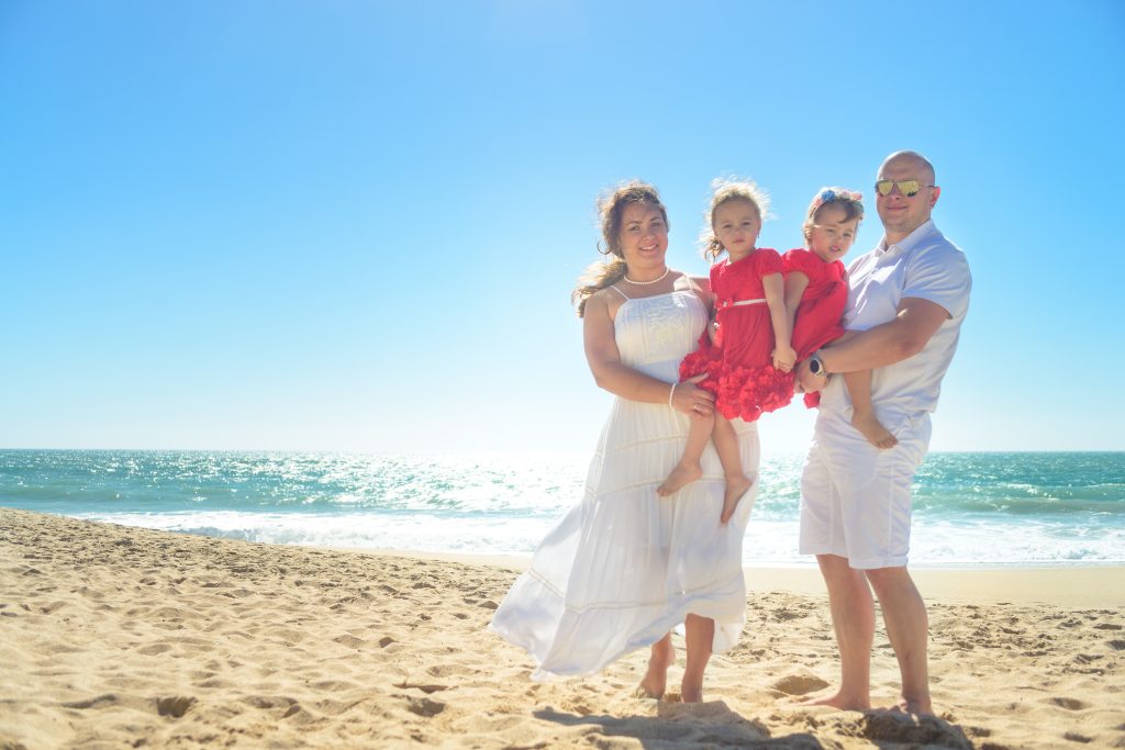 Family hugging and playing on a sunny beach