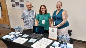 Three Red Hill Registry representatives at a table with laptops and informational materials. Learn what the Red Hill Registry is.